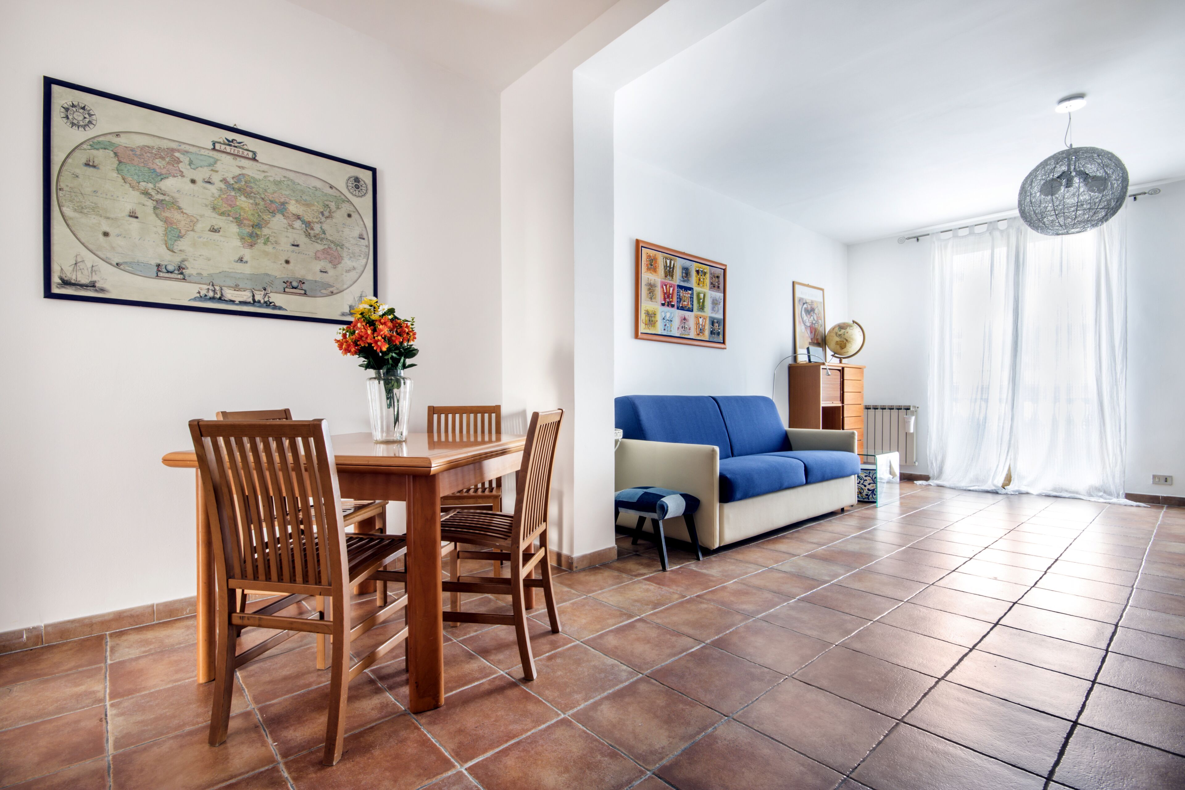 A living room with a dining table, chairs, a sofa, and a globe map on the wall.