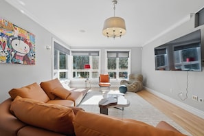 Un salon moderne avec un canapé, une table basse, un fauteuil et un téléviseur fixé au mur.