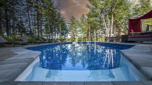 A swimming pool surrounded by trees, with a red canopy and lounge chairs. - Peaceful Retreat on Schmidt Lake (Hammonds Plains)