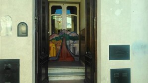 Ein Gebäudeeingang mit Glastür und einer Treppe, die nach oben führt.
