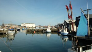 Ein Hafen mit vertäuten Booten, ein Gebäude im Hintergrund und ein klarer Himmel.