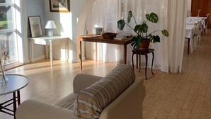 Ein geräumiger Wohnbereich mit einer Couch, einem kleinen Tisch und einer Topfpflanze.