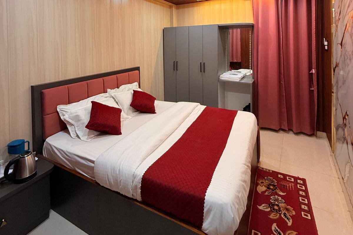 A modern hotel room with a large bed, a wardrobe, a vanity, and a ceiling fan.