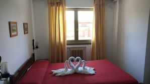 Une chambre d’hôtel avec un lit, des rideaux, un radiateur et une fenêtre.