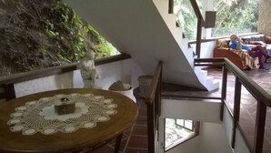 A staircase with a view of a living room, a table with a lace tablecloth, and a statue on the wall. - Green Special B&B (Rio de Janeiro)