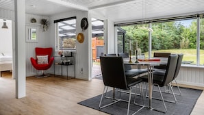 Un interior moderno con comedor, una silla roja y vistas al exterior.