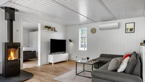Una sala de estar moderna con una chimenea de leña, un televisor de pantalla plana, un sofá y una mesa de comedor.