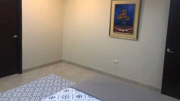 Une pièce avec un tapis à motifs, un tableau encadré, un appareil de climatisation et deux portes.
