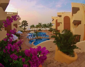 Ein Resort-Poolbereich mit mehreren Pools, Palmen und Liegestühlen.