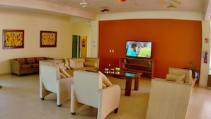 Ein Wohnzimmer mit Fernseher, Sofas, einem Couchtisch und Deckenventilatoren.