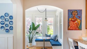 Un coin salon accueillant avec une table ronde, une plante en pot et un tableau accroché au mur.