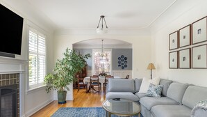Un salon avec une cheminée, un canapé, une table basse et un coin repas comprenant des chaises et une table.