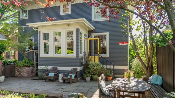 Une maison dotée d’un patio couvert, d’un espace salon extérieur et de plantes en pot.