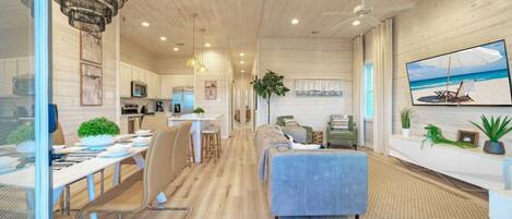 A spacious living area with a large sofa, a dining table, and a kitchen in the background.
