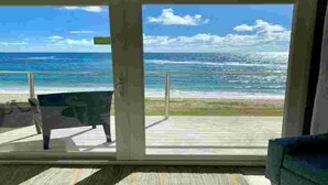 A room with a large window offering a view of the ocean and beach.