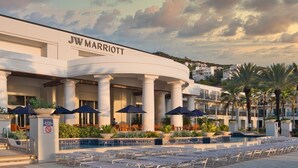 JW Marriott hotel with a pool area, outdoor seating, and palm trees.
