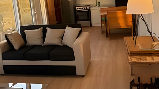 A modern living room with a black and white sofa, a wooden dining table, and a kitchen area with a stove and refrigerator. - Lindas Cabañas En Puerto Varas (Puerto Varas)