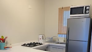 A compact kitchen with a white countertop, a gas stove, a sink, a microwave, and a refrigerator. - Lindas Cabañas En Puerto Varas (Puerto Varas)