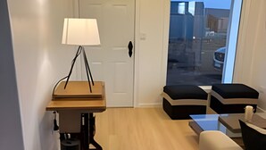 A modern living room with a wooden table, a lamp, a sofa, and a view of the outside through a glass door. - Lindas Cabañas En Puerto Varas (Puerto Varas)