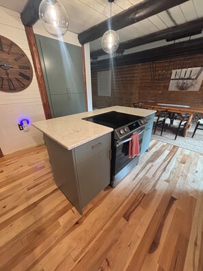Une cuisine équipée d’une cuisinière intégrée, d’un évier et d’un plancher en bois.