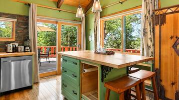 Una cocina con isla de madera, taburetes de bar, un refrigerador y una ventana con vistas a zonas verdes.