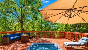 An outdoor deck with a hot tub, seating area, and a large umbrella. - Pinecone Ridge (Big Bear Lake)