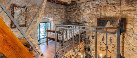 A rustic interior with stone walls, a wooden staircase, and metal railings.