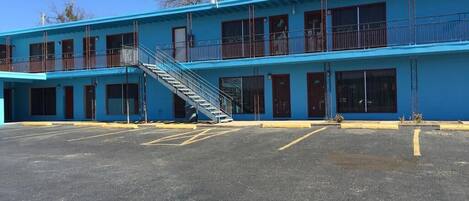 A two-story motel with a blue exterior, a central staircase, and a parking lot.