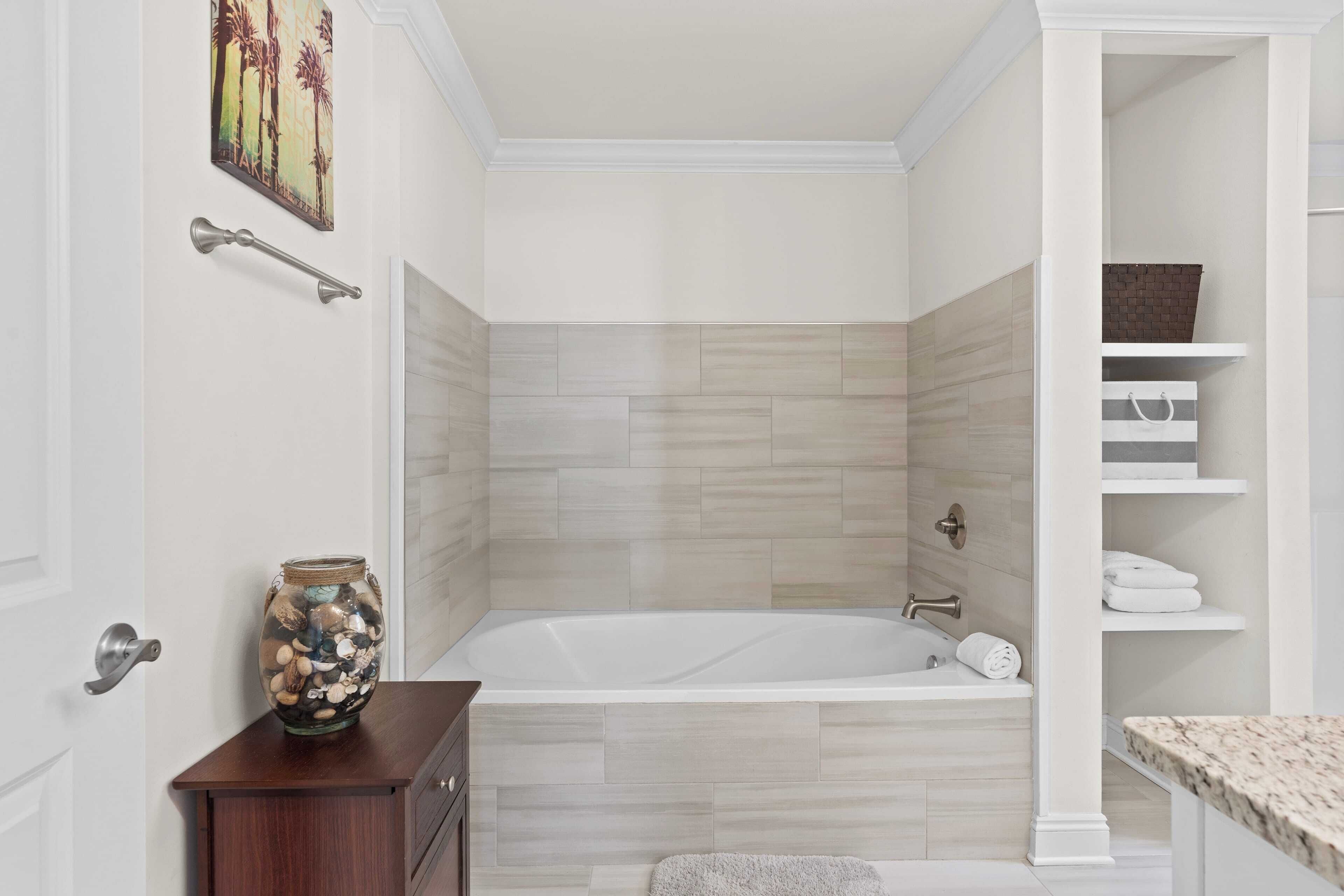 Un baño con bañera, un armario de madera, un perchero y un estante con toallas.