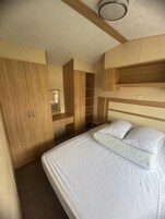 Un dormitorio con cama, armario de madera y estanterías empotradas.