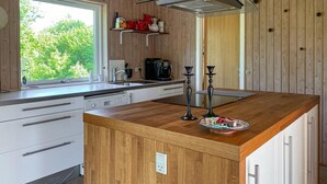 A modern kitchen with a wooden island, white cabinetry, and a window overlooking greenery. - Gorgeous home in Glesborg with WiFi (Glesborg)