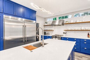 Een moderne keuken met blauwe kastjes, roestvrijstalen apparatuur en een groot eiland.