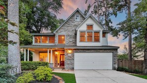 A two-story house with a stone facade, a front porch, and a garage. - The Woodlands Gem- Heated Pool+Spa, EV Charging, Baby Crib, Ping Pong, Grill (The Woodlands)
