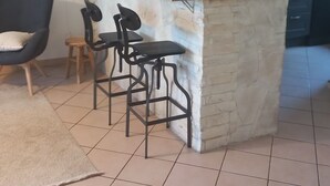 Una cocina moderna con una isla central, taburetes de bar, luces colgantes y un refrigerador.