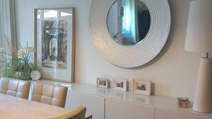 Un comedor moderno con un espejo redondo, obras de arte enmarcadas y un reloj en la pared.