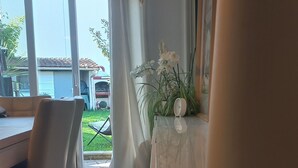 Un comedor con una mesa, sillas, una planta en maceta y vistas al exterior.