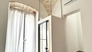 A modern room with a glass door, a staircase, and a built-in air conditioning unit. - MIRA - Casa di Mare is a bright retreat in the heart of Polignano a Mare. (Polignano a Mare)