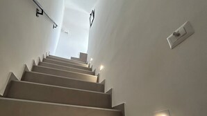 A staircase with a handrail and wall-mounted light fixtures. - MIRA - Casa di Mare is a bright retreat in the heart of Polignano a Mare. (Polignano a Mare)
