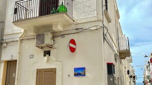 A building with a white facade, a balcony with a metal railing, a 'no entry' sign, and a small blue sign with text. - MIRA - Casa di Mare is a bright retreat in the heart of Polignano a Mare. (Polignano a Mare)