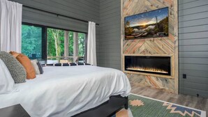 Ein Schlafzimmer mit einem großen Bett, einem Kamin und einem reizvollen Ausblick durch das Fenster.