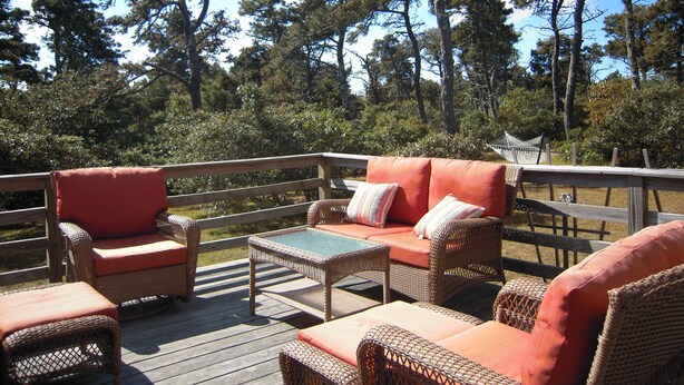 Eine Terrasse im Freien mit Korbmöbeln und einer Hängematte.