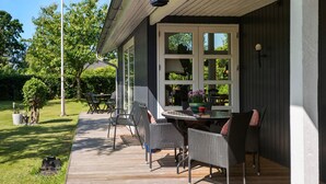 Eine Terrasse im Freien mit Tisch, Stühlen, einer Lampe und Blick auf einen Garten.