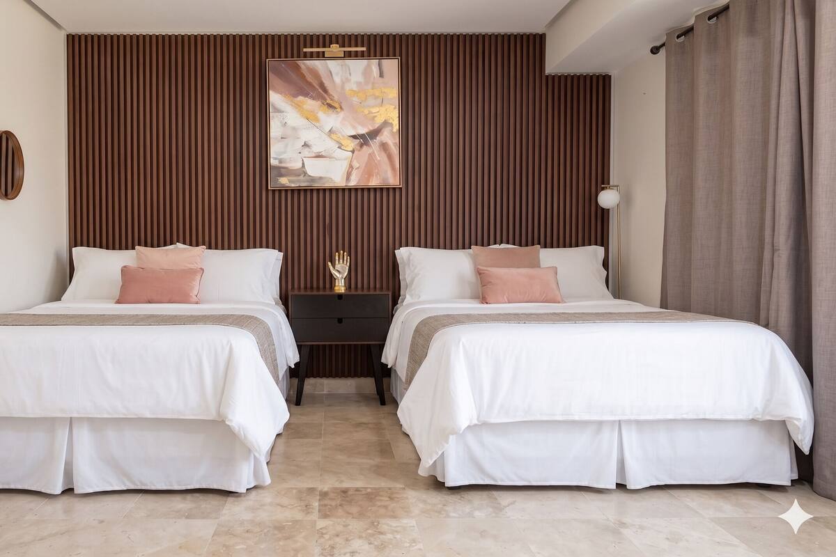 A double room with two beds, a nightstand, a wall-mounted artwork, and a curtain.