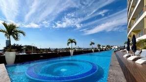 A swimming pool with a circular design, surrounded by lounge chairs and palm trees. - Deck12 Casino and Resort by Monyxbnb (Puerto Vallarta)