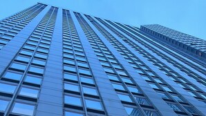 Een hoog gebouw met een modern architectonisch ontwerp, met een raster van ramen en een opvallende centrale ingang.