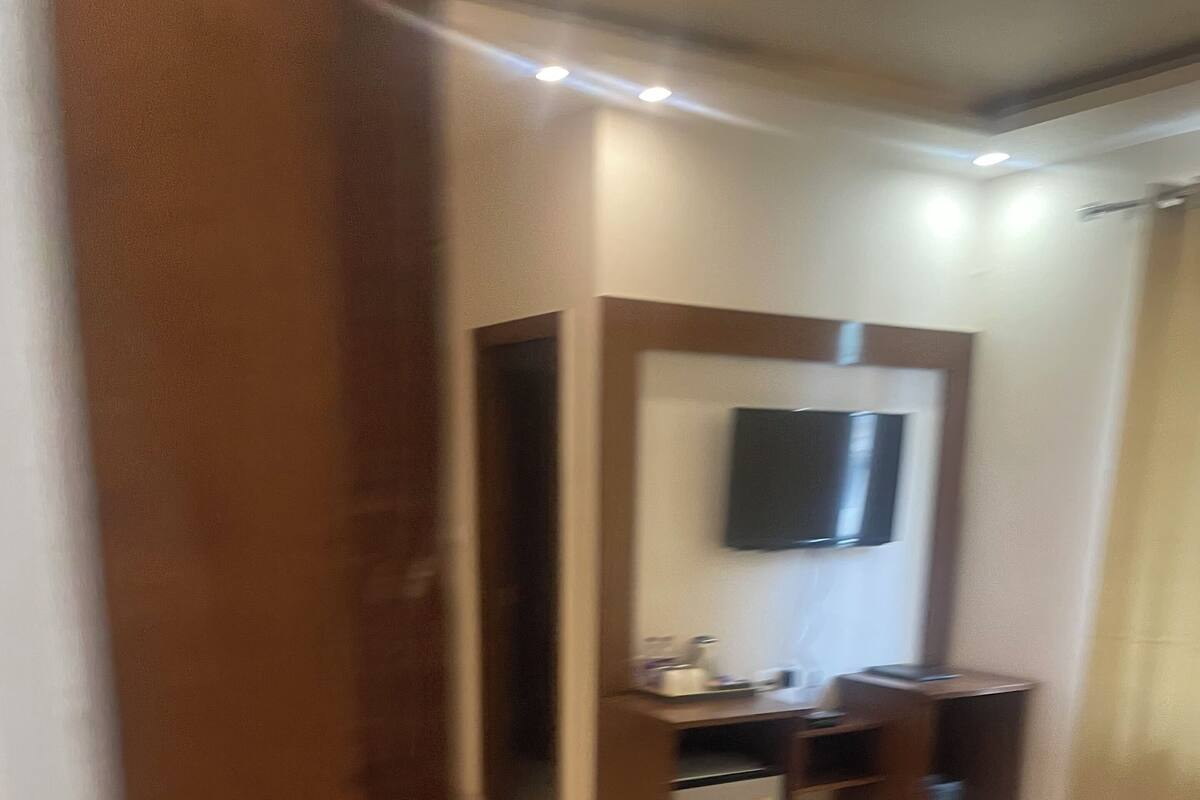 A hotel room with a bed, a desk, a chair, and a TV mounted on the wall.