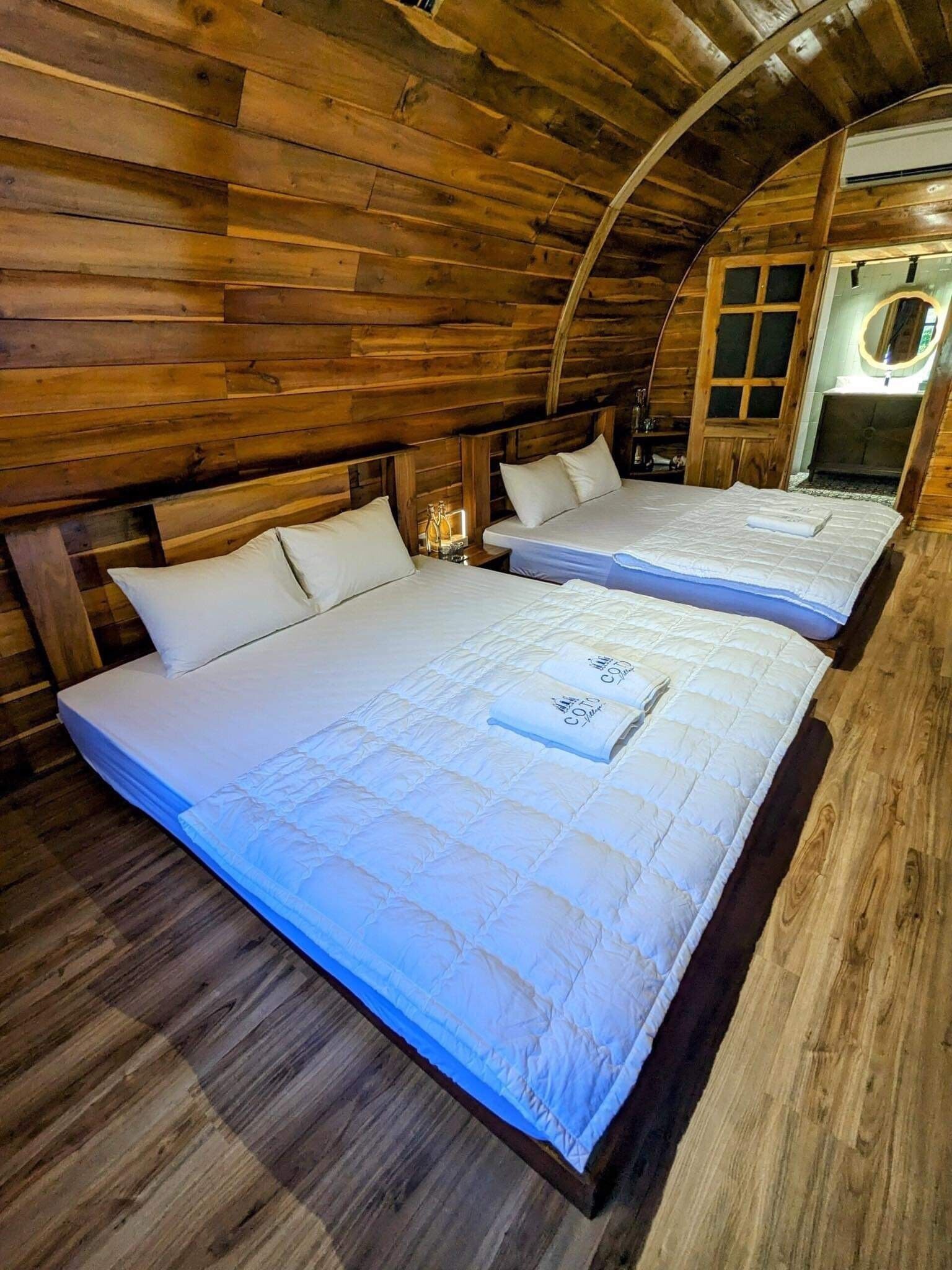 Un dormitorio estilo cabaña con dos camas, paredes de madera y techo curvo.