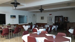Un área de comedor con mesas y sillas, una pizarra y una estantería.