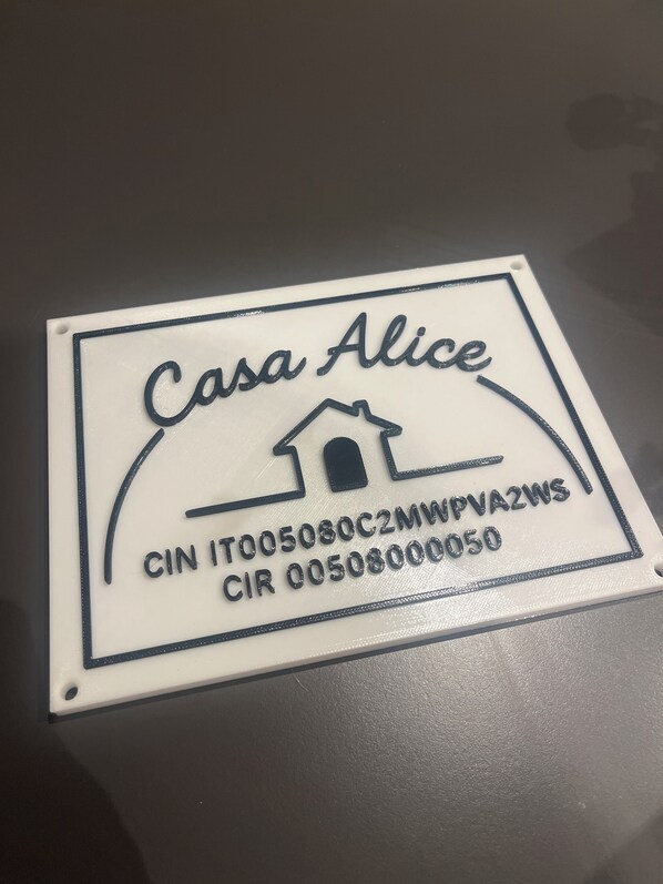 A white sign with "Casa Alice" and a house icon, along with contact information.