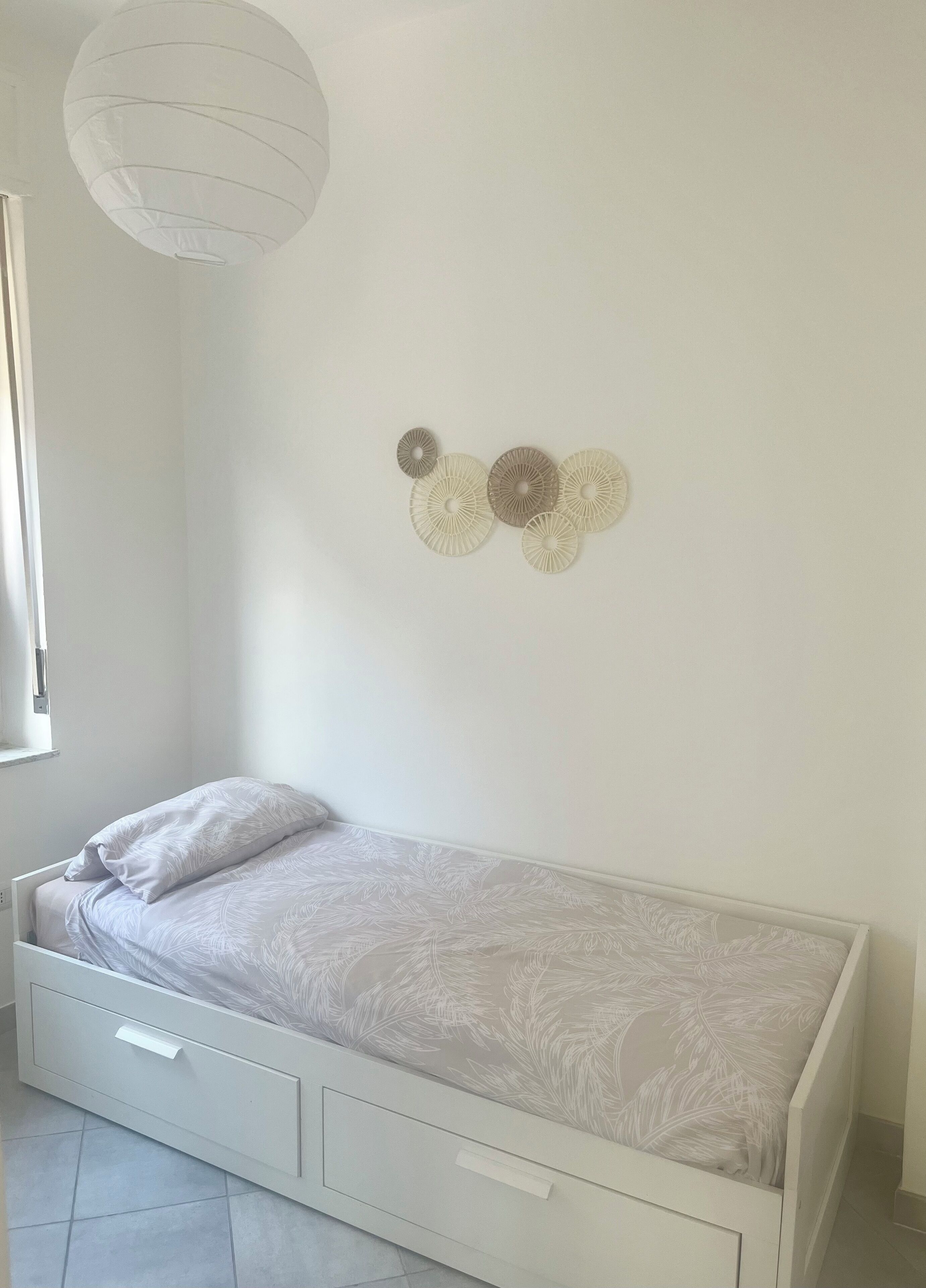 Ein kleines Zimmer mit einem Einzelbett, einem Nachttisch und einem Wanddekor.